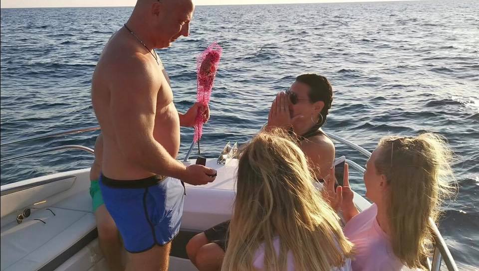 Romantic marriage proposal happening on luxury boat deck with couple engaged on the sea